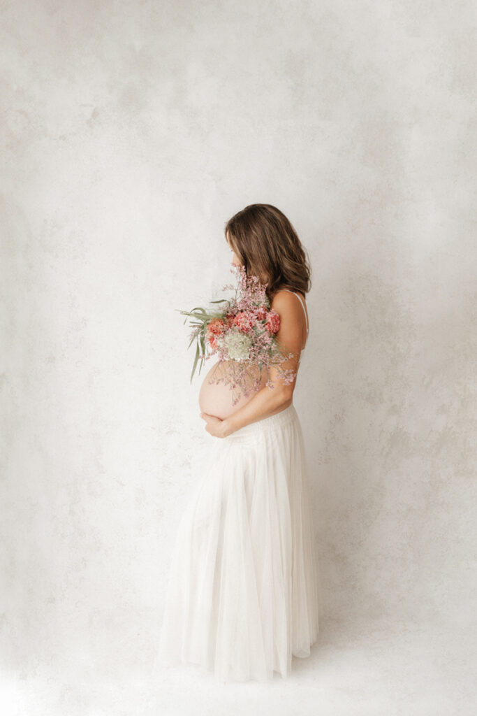 Babybauch Fotostudio mit blumen und weissen rock