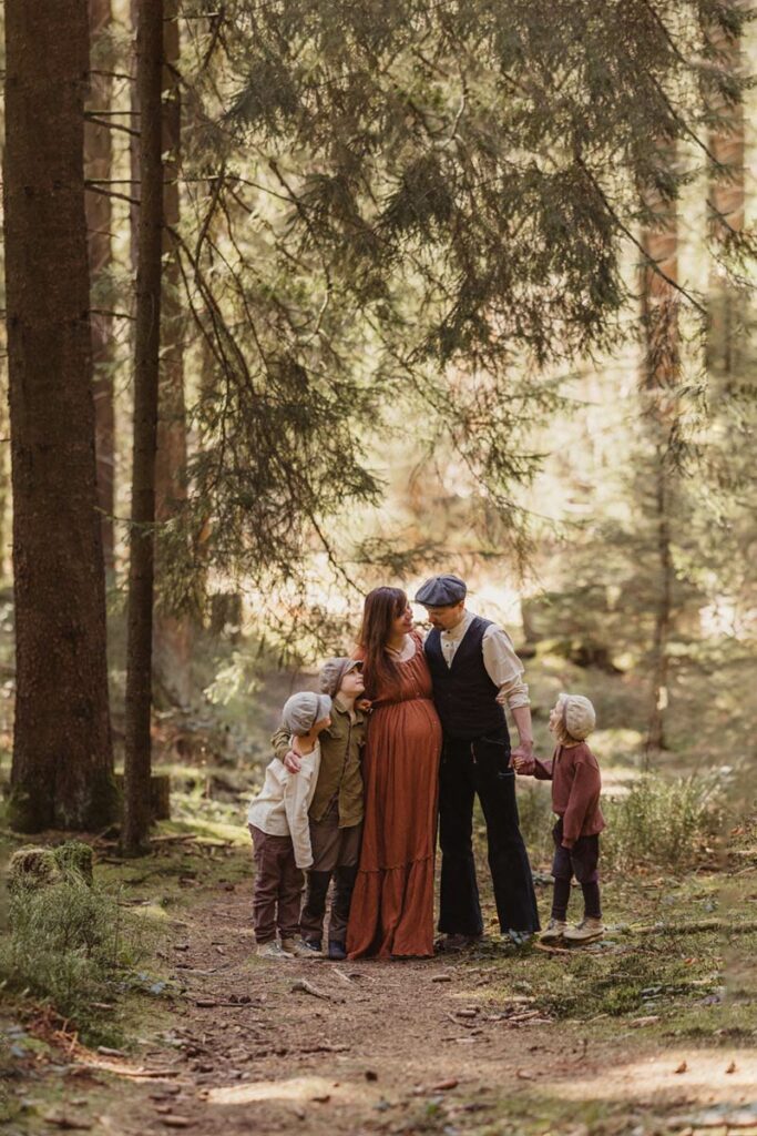 familie babybauch fotoshooting mit 3 kindern stehen im schaumburger wald alles grün idyllisch in der natur