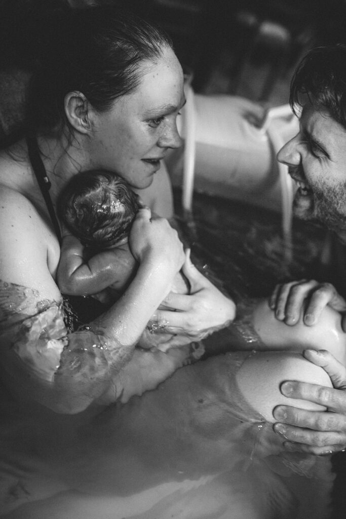 Geburtsfotografie begleitend während Hausgeburt im Geburtspool und Eltern sind überglücklich